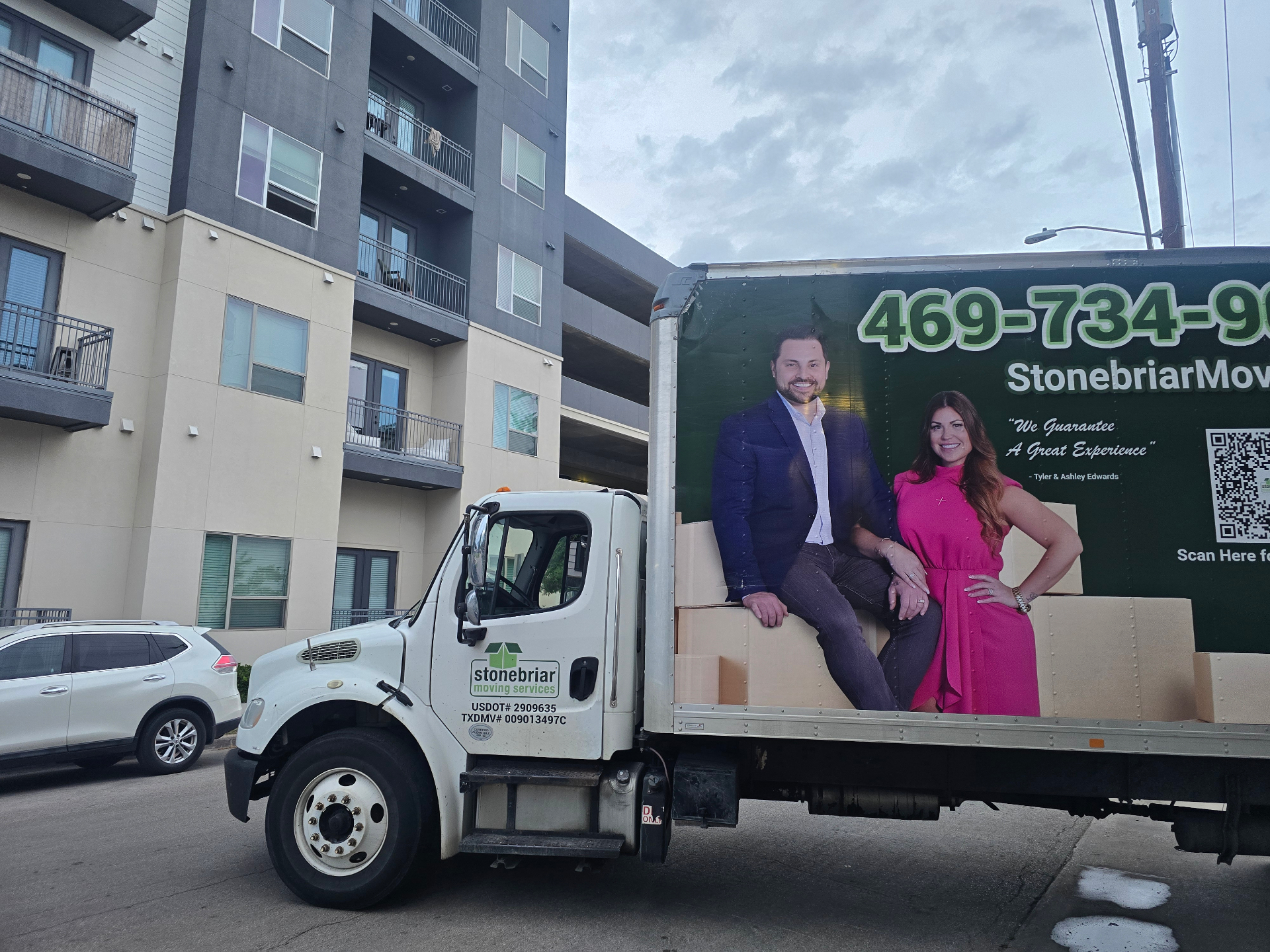 Stonebriar Moving Services truck parked at an Uptown Dallas high-rise apartment building
